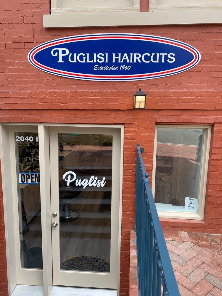 Current Puglisi entrance on I Street: cream door, oval sign, iron rail