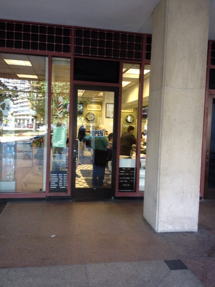 Archival storefront window showing hours and an older price list