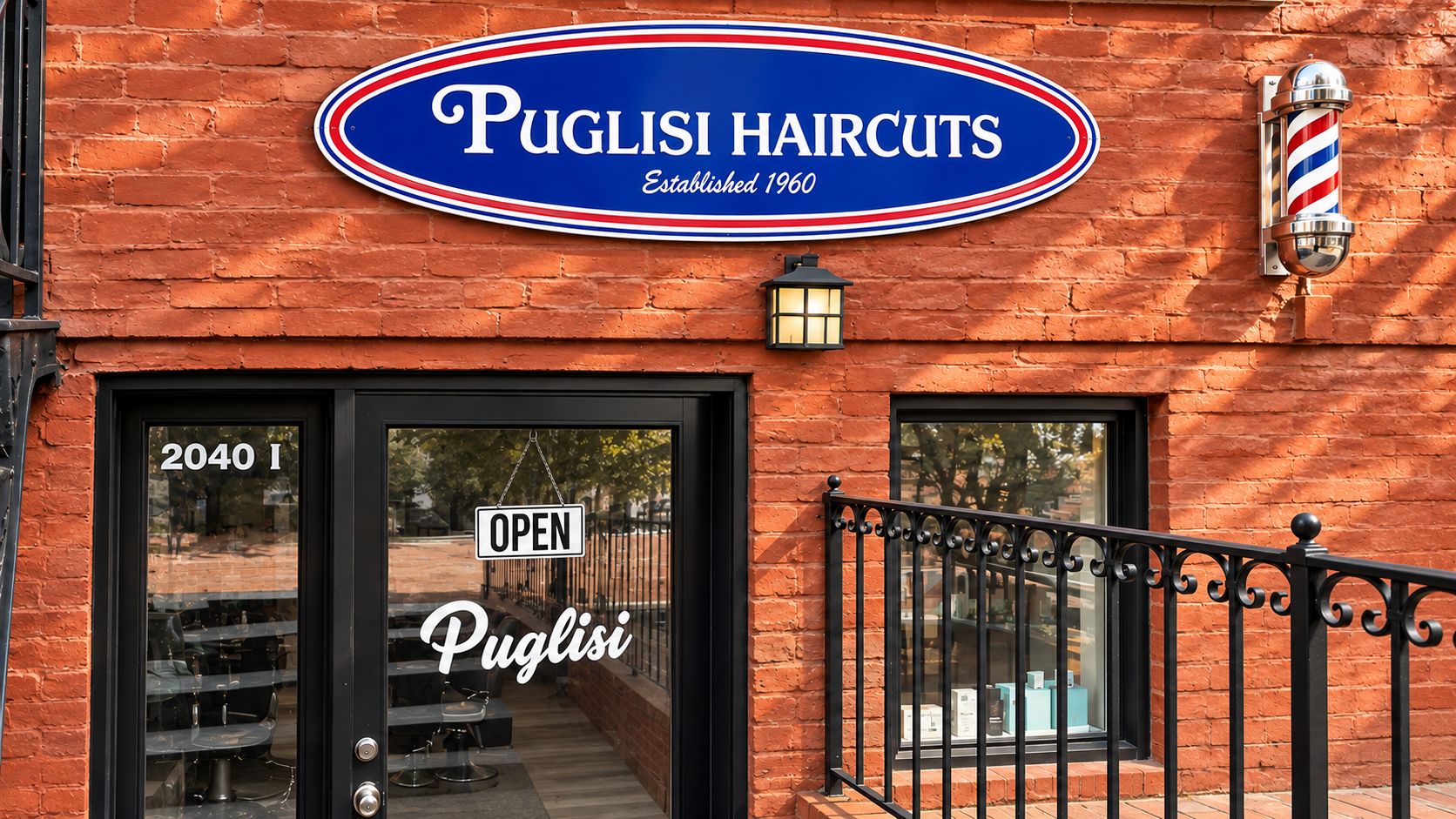 Puglisi HairCuts storefront at 2040 I St NW: oval blue “Puglisi HairCuts, Established 1960” sign and barber pole on the red brick facade, above the glass door lettered 2040 I and Puglisi, with an OPEN sign